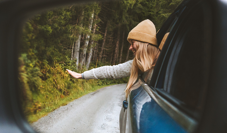 A happy girl waving from her dream car.