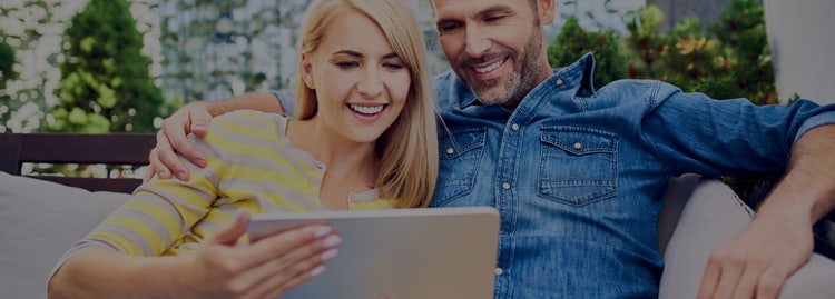 A couple smiling looking at their laptop. Contact Maxxia Salary Sacrifice team today and you could save on tax.